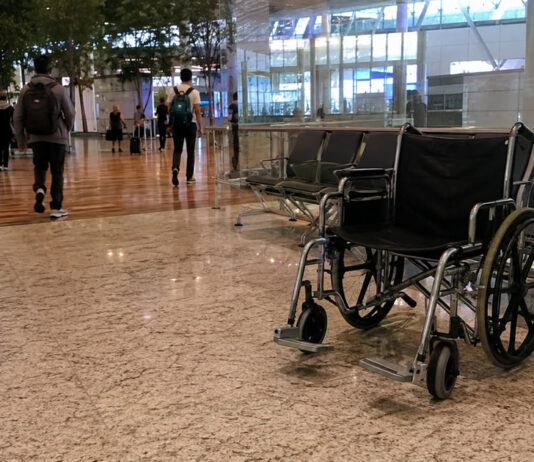 An empty wheelchair in a Singapore airport terminal departure hall