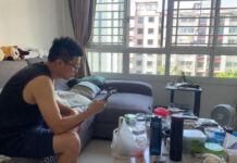 A man in a Singapore HDB living room looking at a smartphone