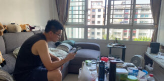 A man in a Singapore HDB living room looking at a smartphone