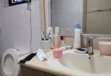 A typical Singapore bathroom vanity with an unlabelled pink facial cream jar among everyday toiletries