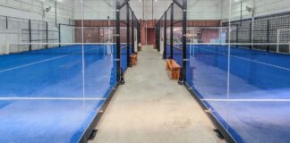 Empty indoor padel courts with blue turf and glass walls, non-literal stock for a sports-gear investment dispute