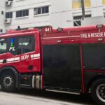 Red SCDF fire engine marked FIRE & RESCUE RESPONSE parked outside an HDB block after a residential fire response