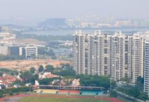 Hazy view over a Singapore neighbourhood sports field and HDB blocks