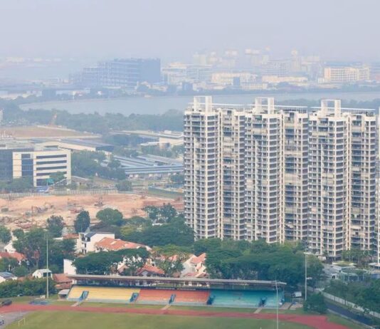 Hazy view over a Singapore neighbourhood sports field and HDB blocks