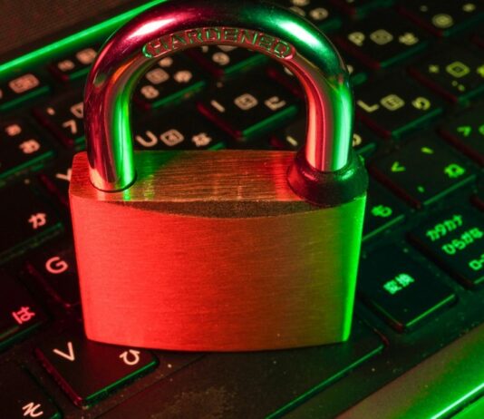 Padlock resting on a laptop keyboard representing ransomware and payroll data security