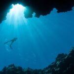 Scuba diver silhouette in underwater cave light representing diving in Palau