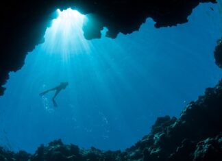Scuba diver silhouette in underwater cave light representing diving in Palau