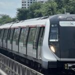 Singapore MRT train on elevated track with residential blocks behind