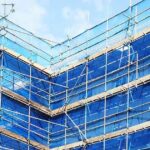 Blue scaffold safety netting on building exterior scaffolding, illustrating fire-retardant netting requirements from March 2027