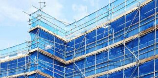 Blue scaffold safety netting on building exterior scaffolding, illustrating fire-retardant netting requirements from March 2027