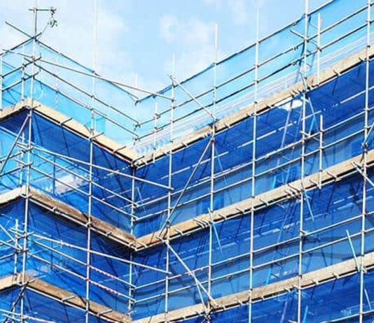 Blue scaffold safety netting on building exterior scaffolding, illustrating fire-retardant netting requirements from March 2027
