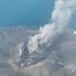 Mount Anak Krakatau erupting with an ash plume over the sea