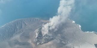 Mount Anak Krakatau erupting with an ash plume over the sea
