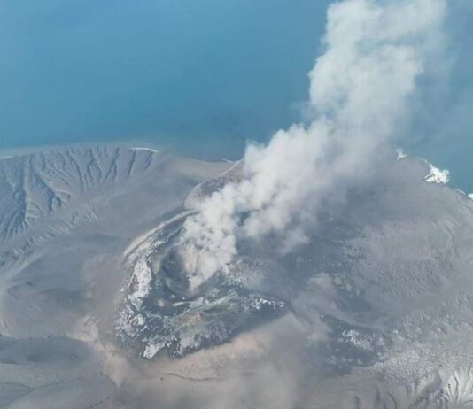 Mount Anak Krakatau erupting with an ash plume over the sea