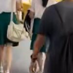 Screengrab of man in black-rimmed glasses walking behind students near Marymount MRT