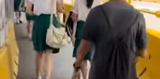 Screengrab of man in black-rimmed glasses walking behind students near Marymount MRT