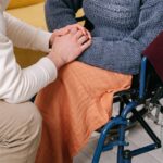 Caregiver holding the hands of a person in a wheelchair (stock photo: Ivan S / Pexels)