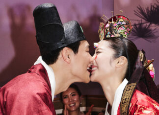 Couple in traditional Korean wedding attire kissing at their ceremony