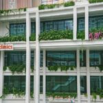 Haze Treatment Fees Capped at S$10 for Eligible Singaporeans From 12 Oct Exterior of Punggol Polyclinic at Oasis Terraces in Singapore, with the orange SingHealth Polyclinics sign on its green, plant-covered facade (Photo: Deoma12 / Wikimedia Commons, CC BY-SA 4.0).