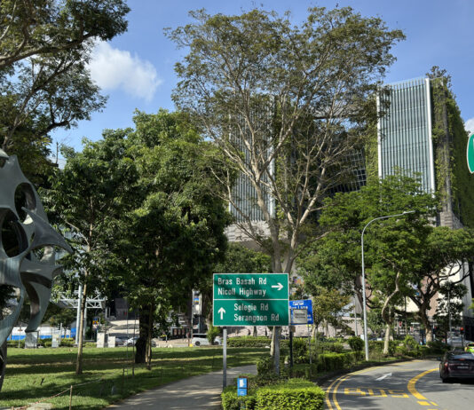 Prinsep Street road sign beside a sculpture, trees and a road junction