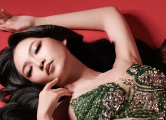 Portrait of a woman in a green beaded gown lying against a red background