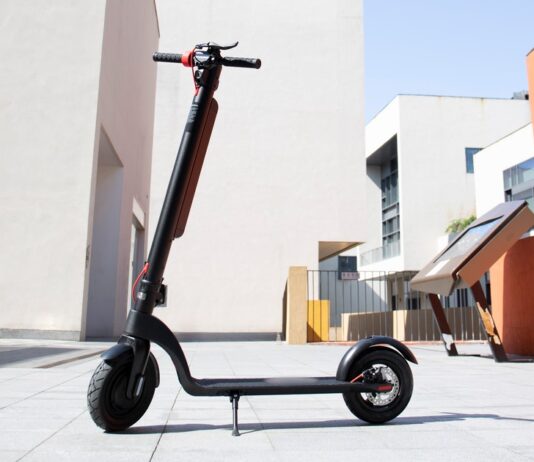 Parliament Passes Online Sales Ban for Non-Compliant Mobility Devices & New Battery Safety Rules Illustrative photo of an electric kick scooter with a battery pack on its stem, standing in an empty paved plaza (Photo: Claybox / Wikimedia Commons, CC BY-SA 4.0)