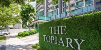The entrance sign of The Topiary condominium in Sengkang, set on a green hedge wall in front of the condo blocks (Photo: Qingjian International via 8world)