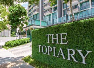 The entrance sign of The Topiary condominium in Sengkang, set on a green hedge wall in front of the condo blocks (Photo: Qingjian International via 8world)