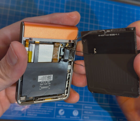 Hands holding a opened Ledger hardware wallet device with its back cover removed