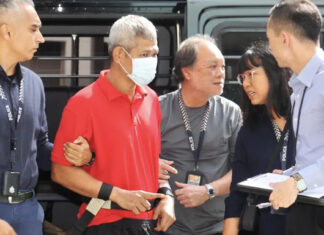 Affendi Yusoff escorted by police officers beside a police vehicle